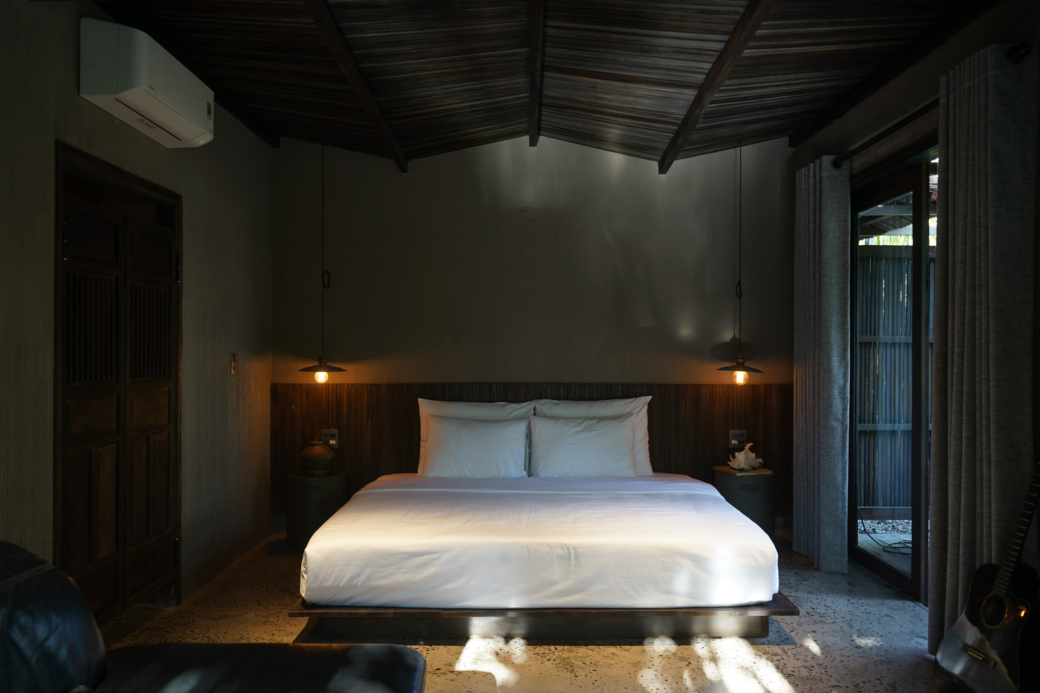 Phòng ngủ với giường đôi, nội thất gỗ và cửa kính nhìn ra vườn